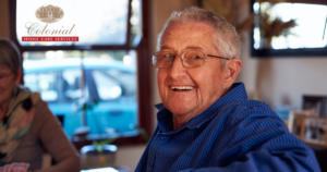 A senior man is happy at home as a result of successful long-distance caregiving.
