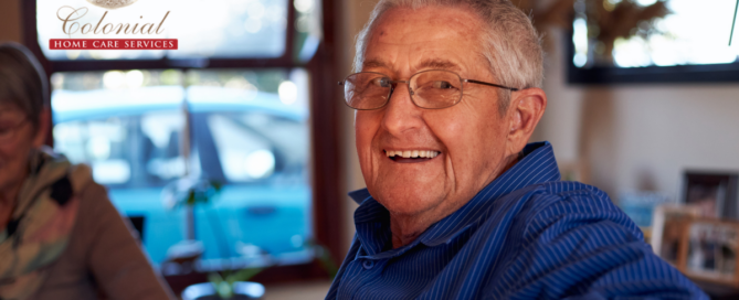 A senior man is happy at home as a result of successful long-distance caregiving.