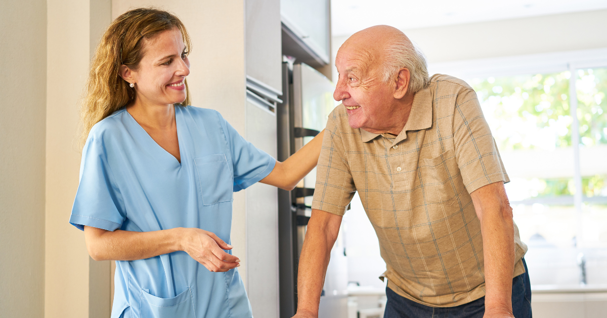 Caregiver providing senior home care services smiling at senior man using a walker