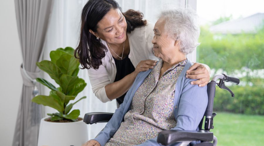 A caregiver helps a senior in a wheelchair representing home care for adults with disabilities.