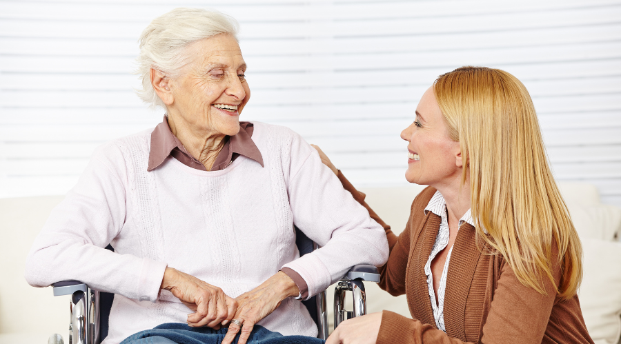 A caregiver kindly talks to a senior in a wheelchair representing Care for Adults with Disabilities in Irvine.
